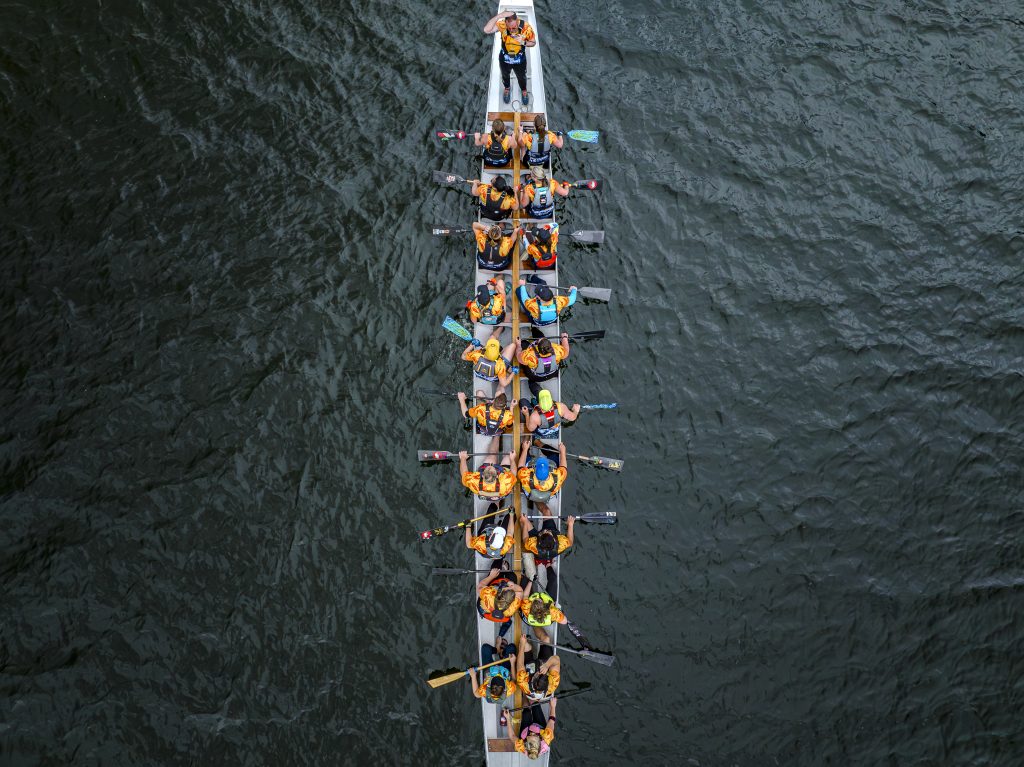 Straight overhead drone shot of the crew paddling in formation